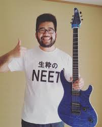 Sithu Aye holds up his guitar with one hand whilst giving a thumbs up with his other hand and smiling